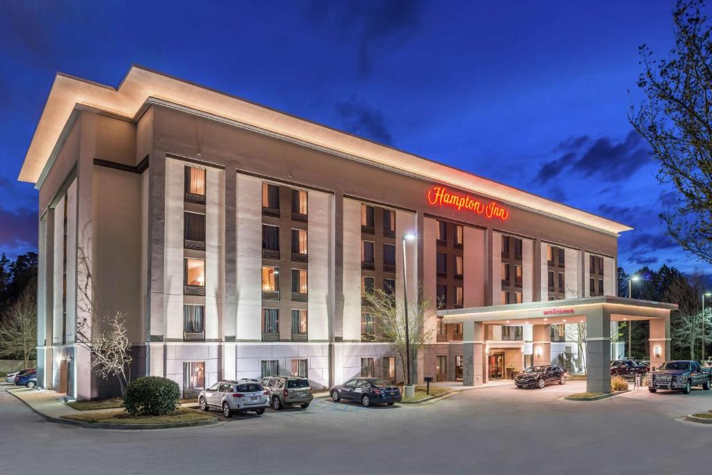 Hampton Inn Columbia Northeast-Fort Jackson Area في كولومبيا: مبنى الفندق مع وجود سيارات تقف في موقف للسيارات