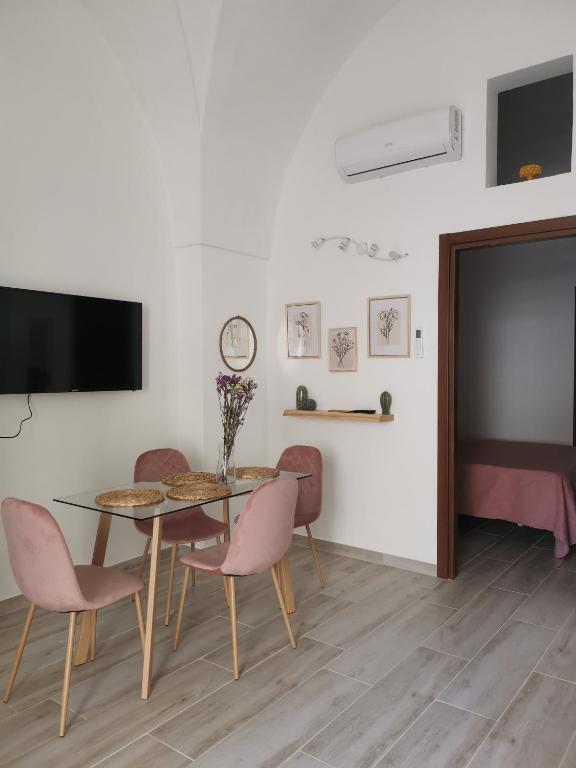 Un comedor con mesa y sillas y un televisor de pantalla plana. en LeVolte, en Brindisi