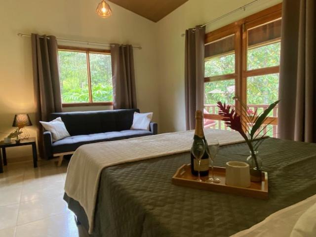 Siquirres Mountain Lodge في Siquirres: غرفة نوم مع سرير وزجاجة من النبيذ