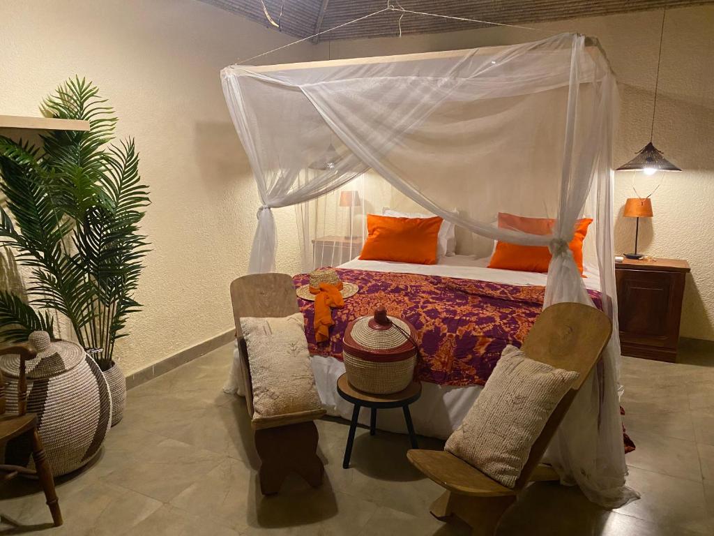 a bedroom with a canopy bed and two chairs at Toubacouta Lodges in Toubakouta