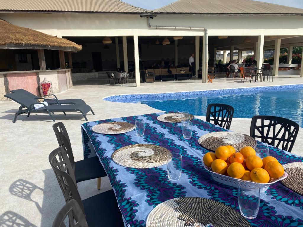 a table with a bowl of oranges next to a pool at Toubacouta Lodges in Toubakouta