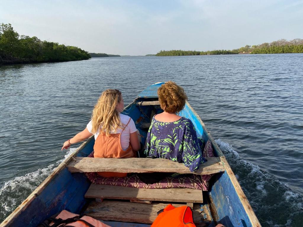 two women sitting in a boat on the water at Toubacouta Lodges in Toubakouta