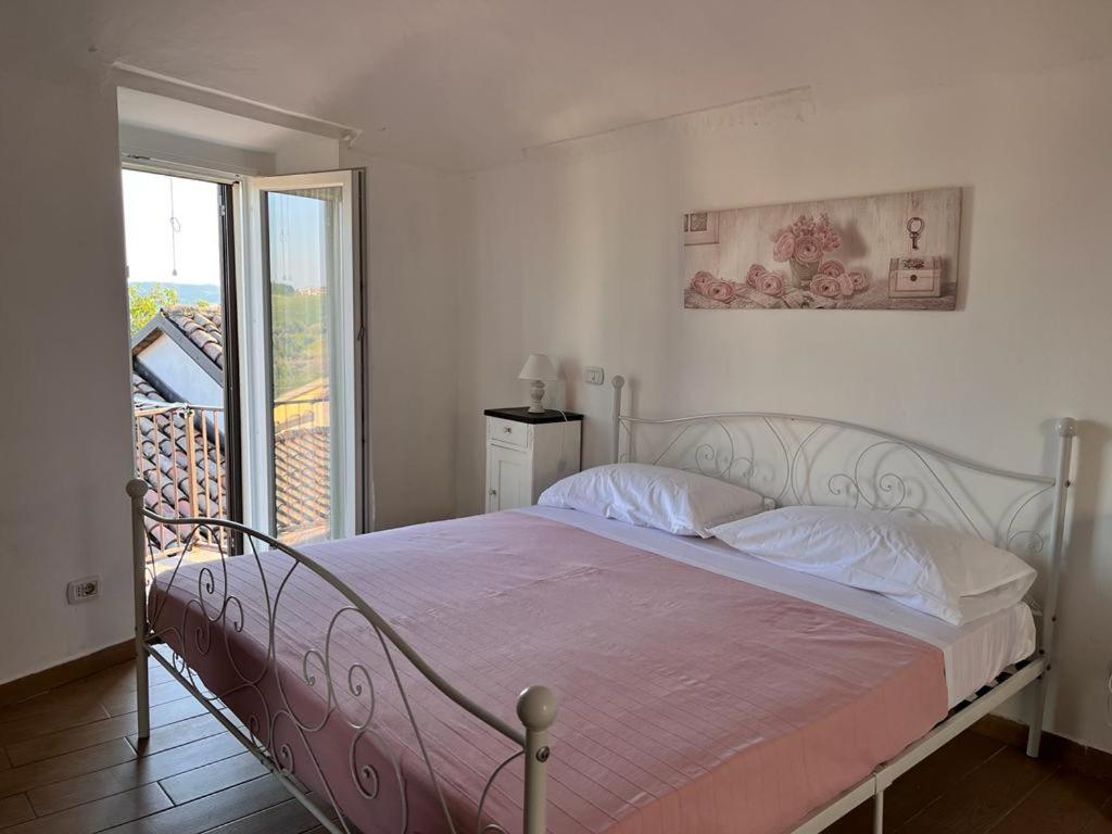a bedroom with a bed with a pink blanket and a window at La Casetta di Treville in Ozzano Monferrato