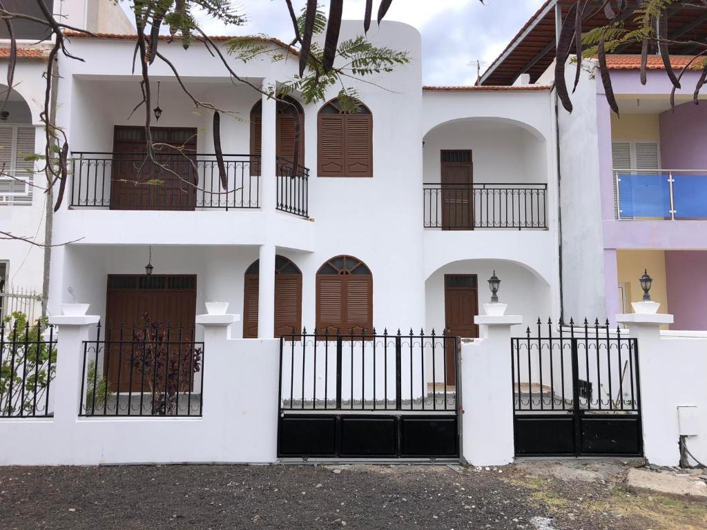 ein weißes Gebäude mit braunen Türen und einem Zaun in der Unterkunft Tarrafal Ecodécor Full House in Tarrafal