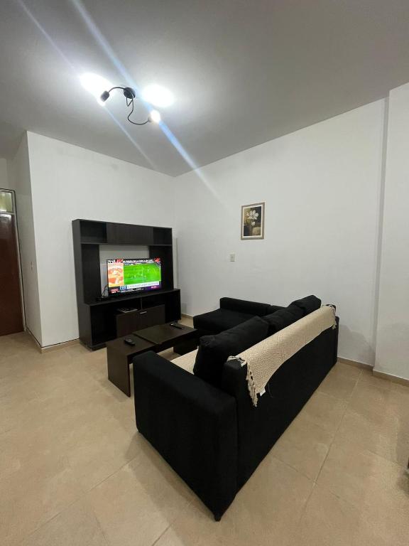 sala de estar con sofá negro y TV en DEPARTAMENTO 412 en Mendoza
