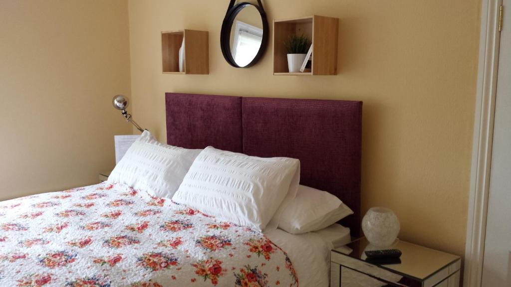 a bedroom with a bed with a floral bedspread and a mirror at The Railway Inn Westerfield in Ipswich