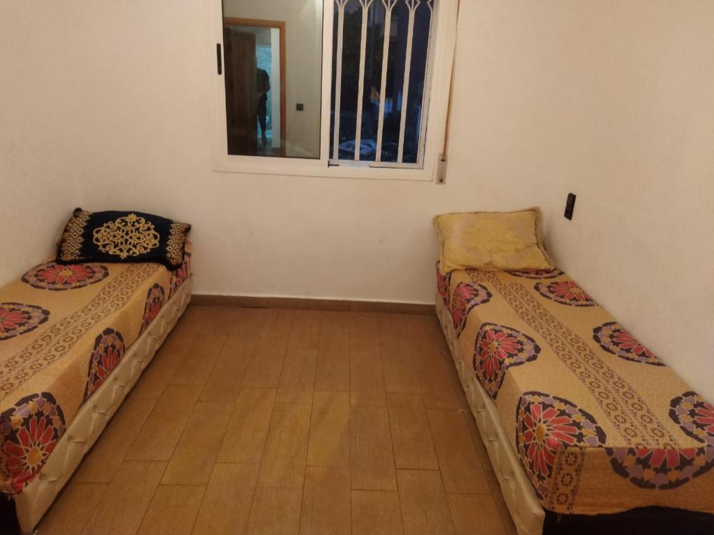 2 Betten in einem Zimmer mit Fenster in der Unterkunft Apartamento in Saidia 