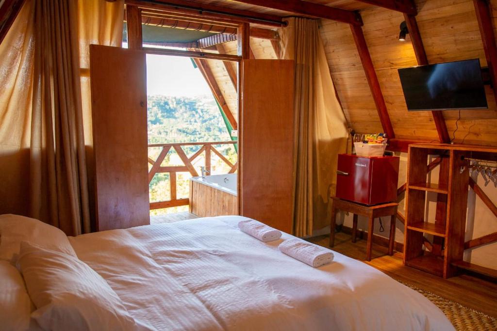 a bedroom with a white bed and a large window at Antahkarana Casa Hotel in San Agustín