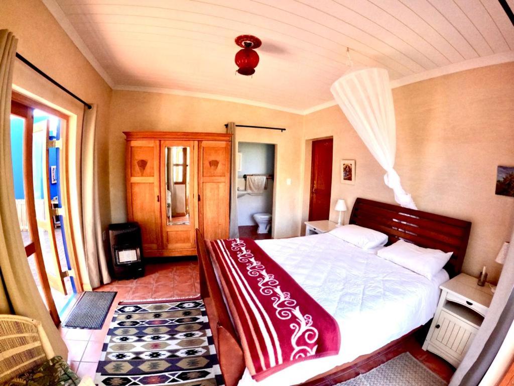 a bedroom with a bed with a red blanket on it at Willow's Rest in Barrydale