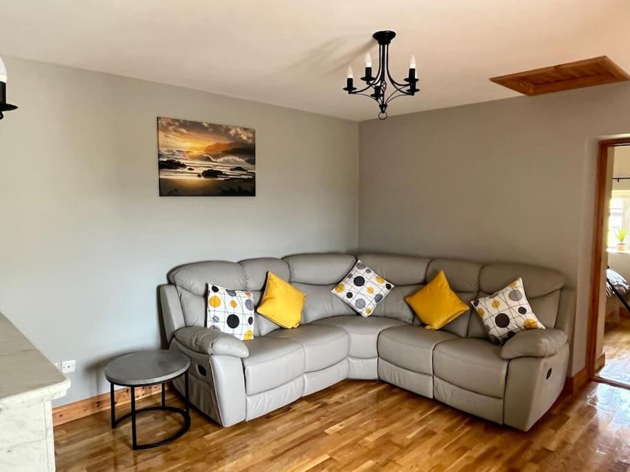 a living room with a gray couch with yellow pillows at Tigh Seoighe - Renovated Cottage Tourmakeady in Toormakeady
