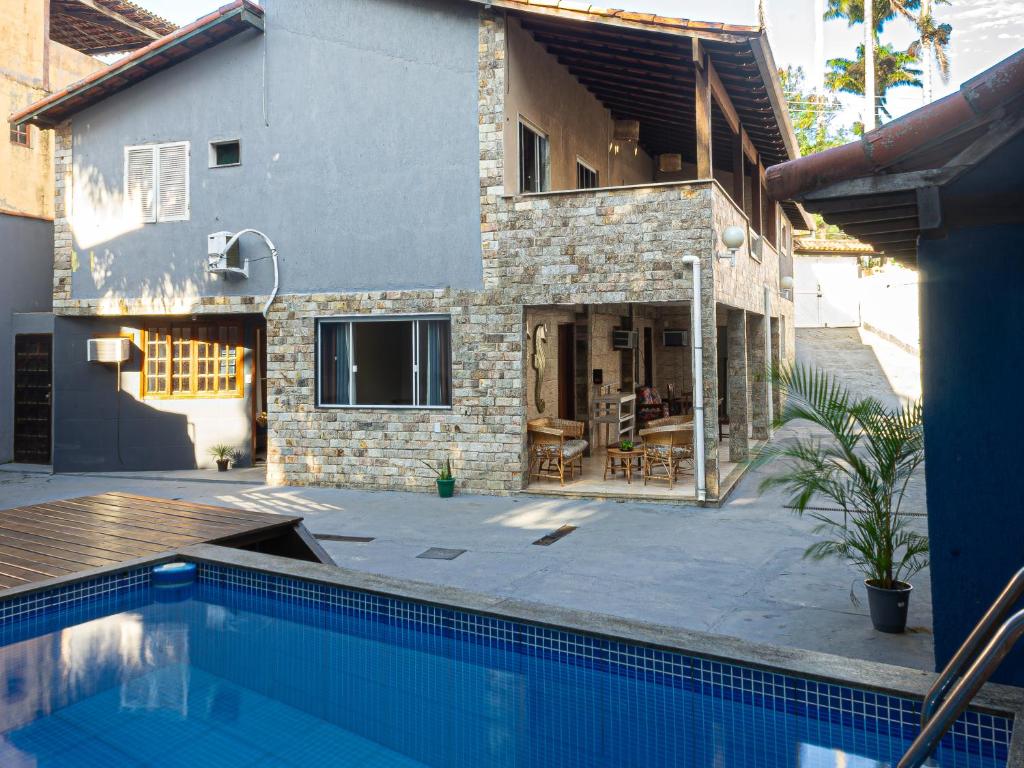 a house with a swimming pool in front of a house at Casa Jaguar suites 150 mt da praia geriba in Búzios