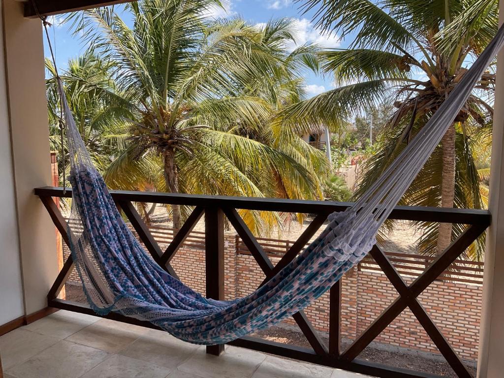 a hammock on a balcony with palm trees at BEACH HOUSE - Apartment 2 - com cozinha - with kitchen in Barra Grande