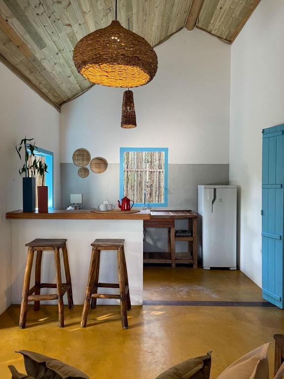 a kitchen with wooden stools and a counter with a refrigerator at Minha Casa em Caraíva in Caraíva