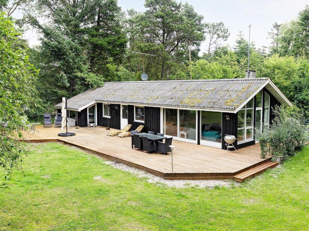 a house with a large wooden deck in a yard at Holiday home Jerup VII in Jerup