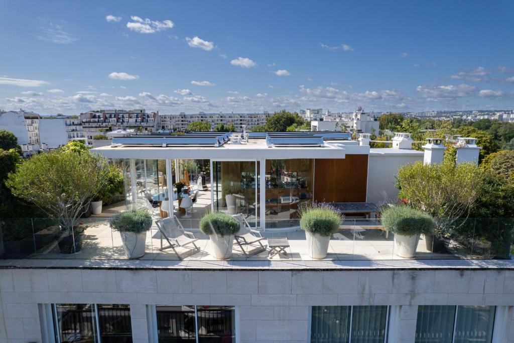 a building with potted plants on the roof at Splendid apartment and rooftop overlooking Paris - Neuilly - Welkeys in Neuilly-sur-Seine