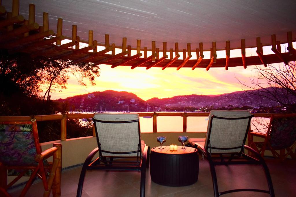 a patio with two chairs and a table with a view at Casa de Ali: Located on the beach! in Zihuatanejo