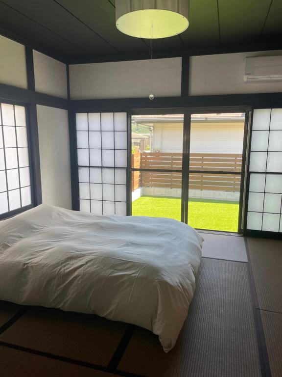 a bedroom with a large white bed and windows at 貸切古民家Yukan in Sengokuhara