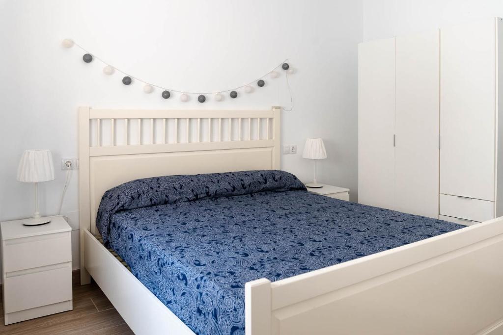 - une chambre blanche avec un lit et une couette bleue dans l'établissement Ático en alhaurin de la torre, à Malaga