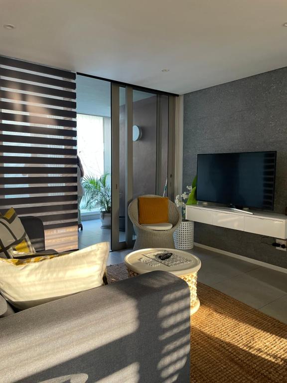 a living room with a television and a couch and chairs at Umhlanga Ocean Dunes in Umhlanga
