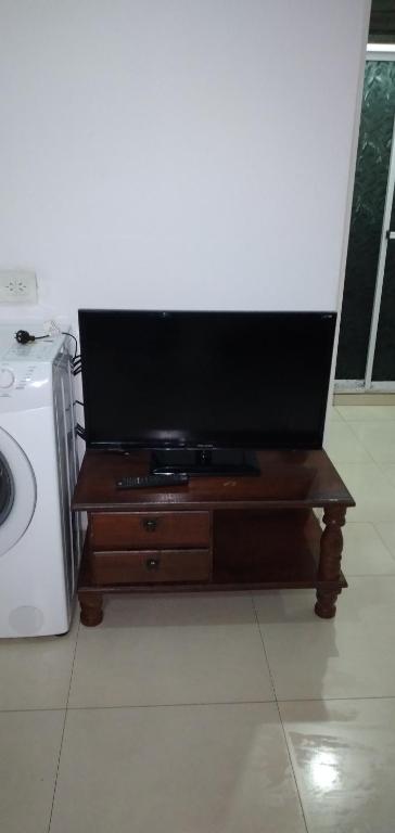 een flatscreen-tv op een houten standaard naast een wasmachine bij 3 cuadra polideportivo in San Vicente