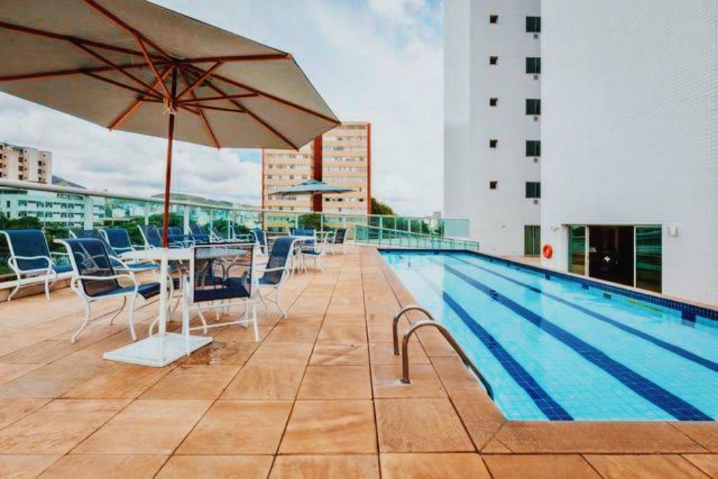una piscina con mesa, sillas y sombrilla en BH PARA 2 - HOTEL LUXO Apartamento Particular Savassi, en Belo Horizonte