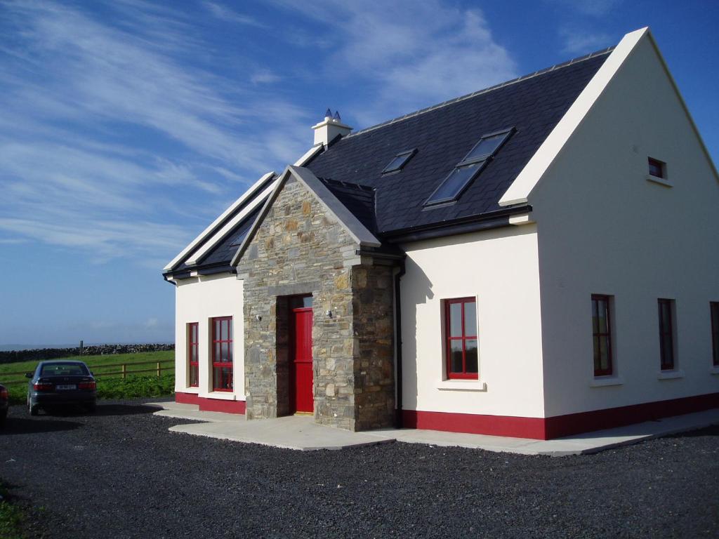 a small white house with a red door at Journey's End in Milltown Malbay