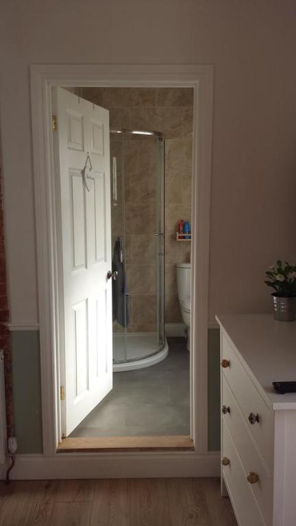 a bathroom with a glass door leading to a shower at The Railway Inn Westerfield in Ipswich