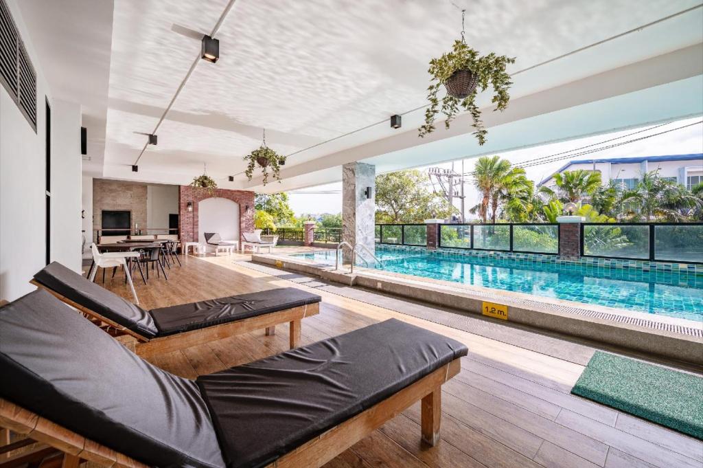 ein offenes Wohnzimmer mit einem Pool und einem Poolhaus in der Unterkunft The Corner Lodge - SHA Extra Plus in Pattaya