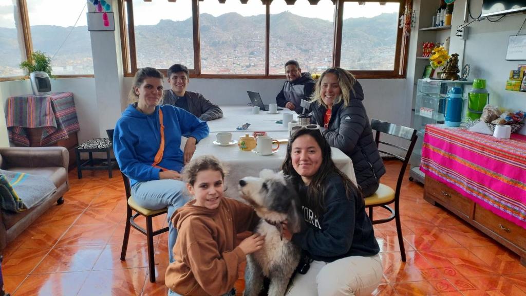 un grupo de personas sentadas alrededor de una mesa con un perro en Black Sheep Hostel Cusco, en Cusco