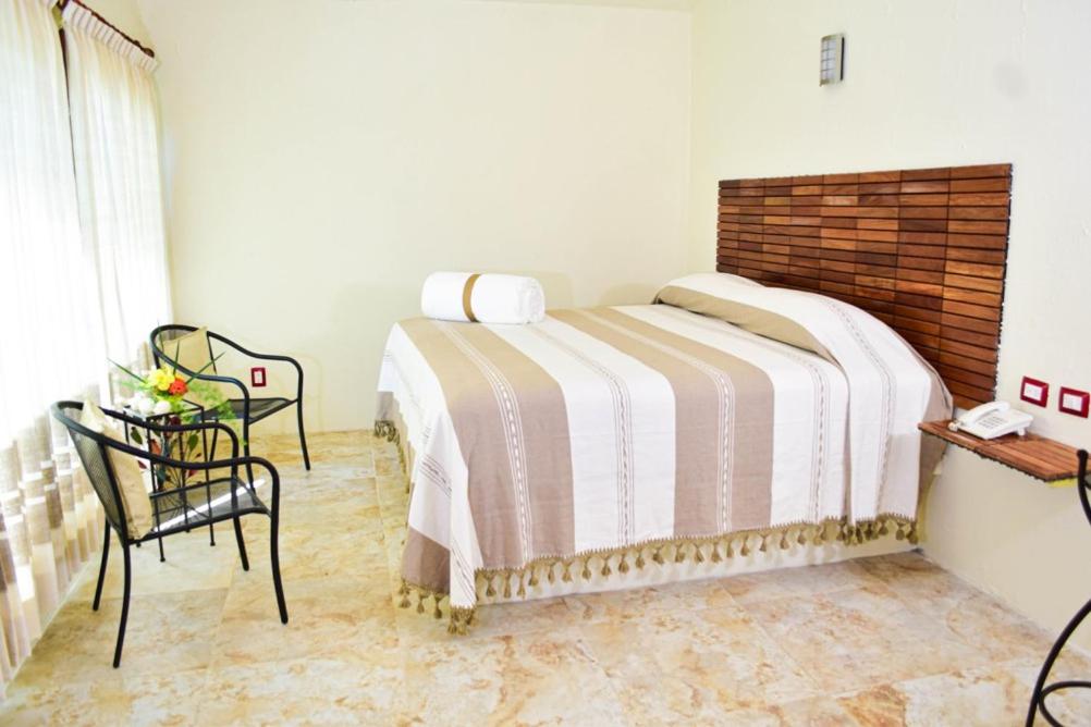 Hotel Campestre Santa Clara في San Juan Bautista Tuxtepec: غرفة نوم بسرير وطاولة وكرسي