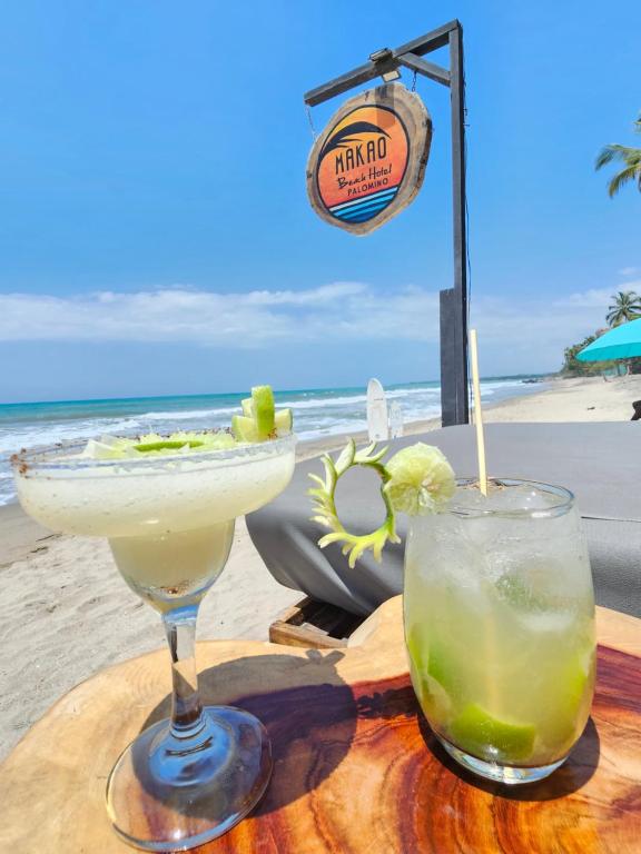 two cocktails sitting on a table on the beach at Makao Beach Hotel in Palomino