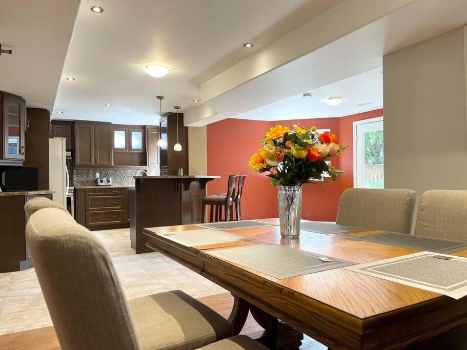 a kitchen and dining room with a table with a vase of flowers at Ella's Cozy Retreat at Richmond Hill in Richmond Hill