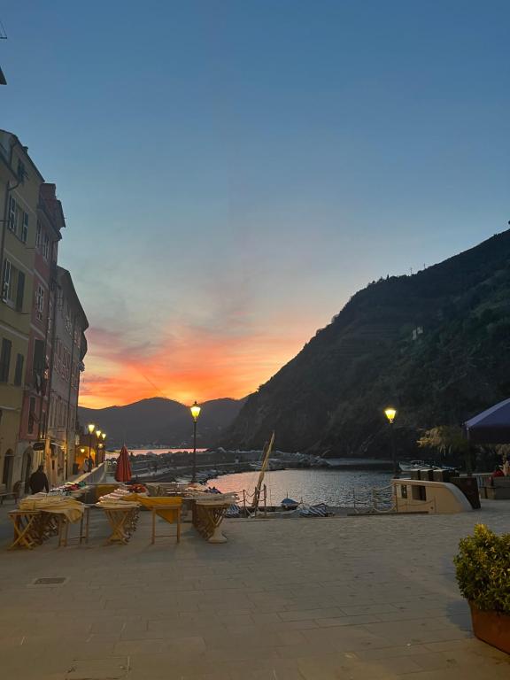 puesta de sol en una playa con mesas y sillas en Lisetta Rooms, en Vernazza