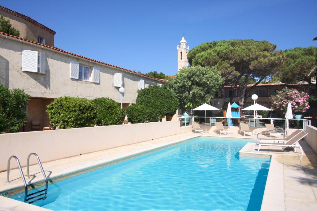 a swimming pool with chairs and a building at Hotel L&#39;ondine in Algajola