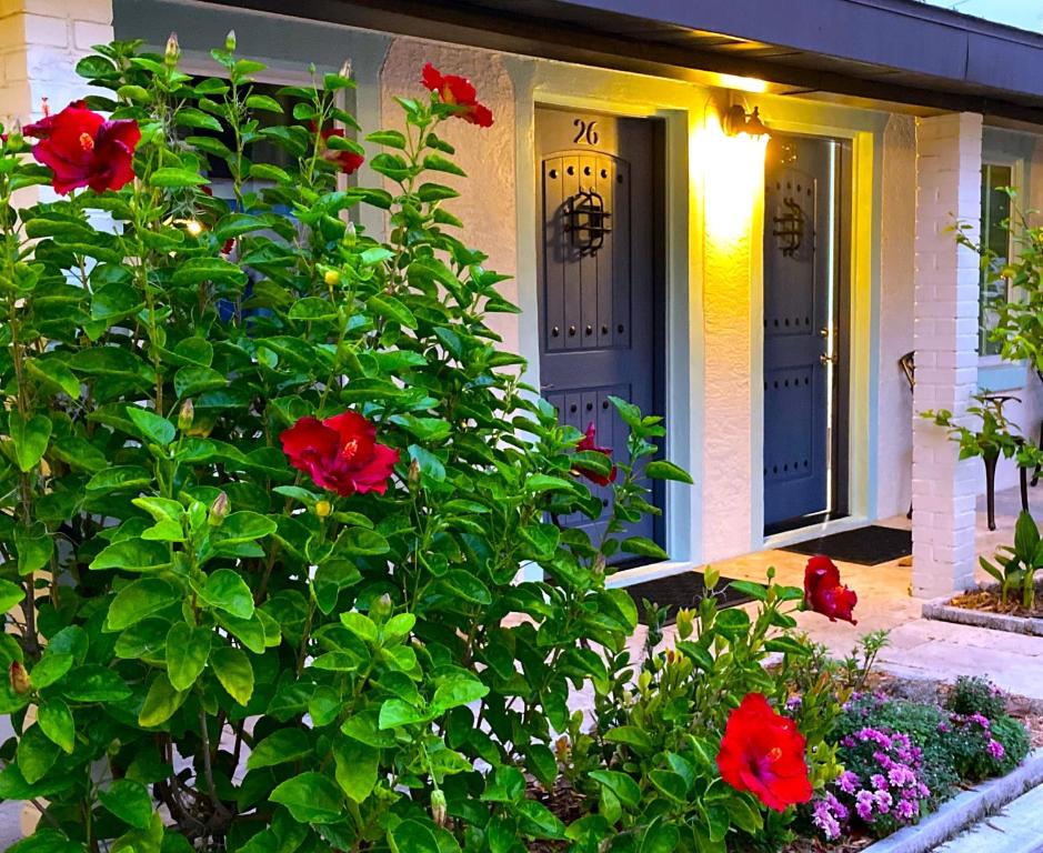 a house with two blue doors and a bush with red flowers at Retreat at Crystal Manatee in Crystal River