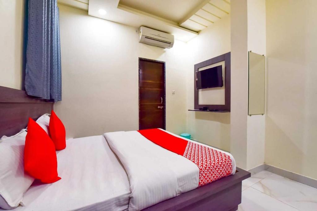 Schlafzimmer mit einem Bett mit roten Kissen und einem TV in der Unterkunft OYO Flagship Hotel Pink Orchid in Kota