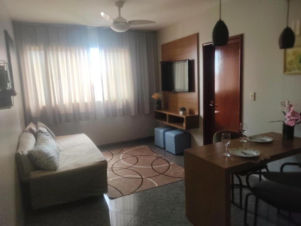 a living room with a couch a table and a television at FLAT FUNCIONAL e ECONÔMICO,CENTRO-GO in Goiânia