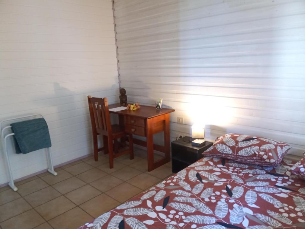 1 dormitorio con cama, escritorio y mesa en Enzo lodge chambre tipanier en Papawa