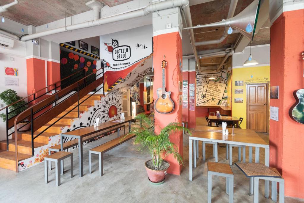 un restaurant avec un escalier, des tables et des chaises dans l'établissement Ostello Bello Mandalay, à Mandalay