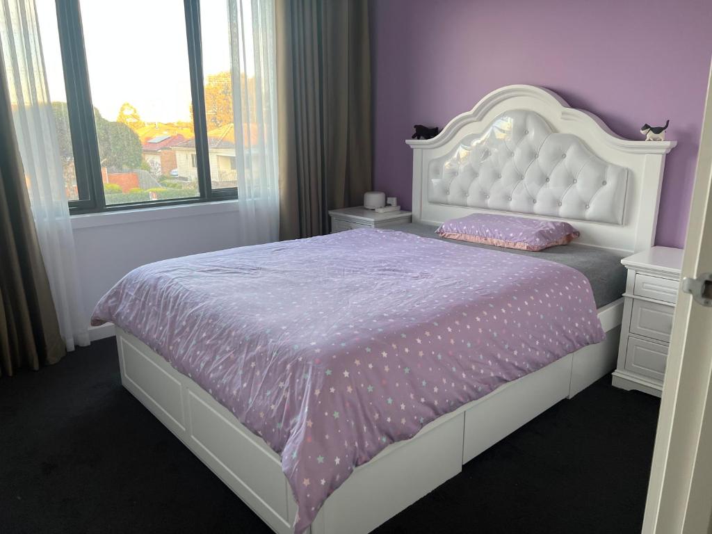 een slaapkamer met een wit bed met paarse lakens en een raam bij Private Rooms in Clayton South Near Monash Uni in Clayton North