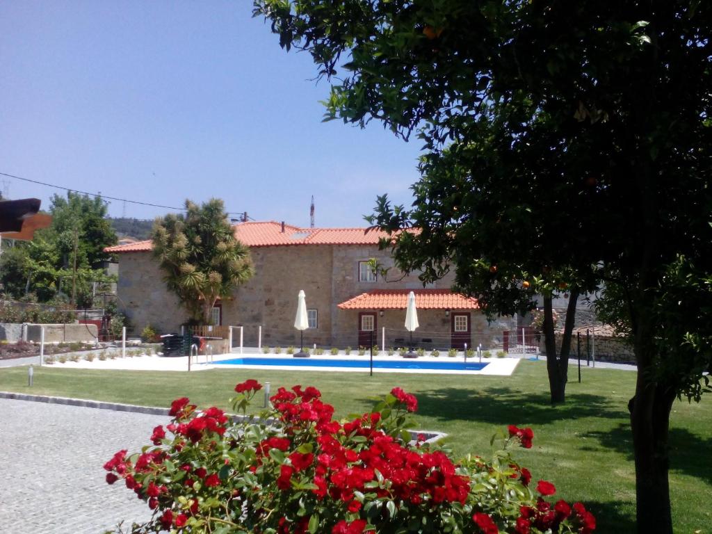 ein Gebäude mit einem Pool und roten Blumen in der Unterkunft Casa Cachada in Braga