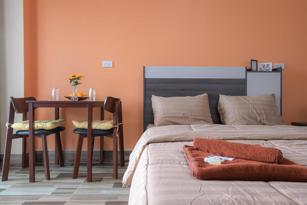een slaapkamer met een bed en een tafel en stoelen bij The Wish Hotel in Chachoengsao