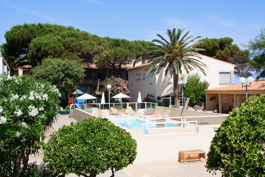 a villa with a swimming pool and palm trees at Hotel L'ondine in Algajola