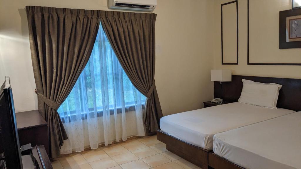 Kampong Alor GajahにあるSerene Holiday Chalet with pool in a quiet enclaveのベッドが2つと大きな窓がある寝室