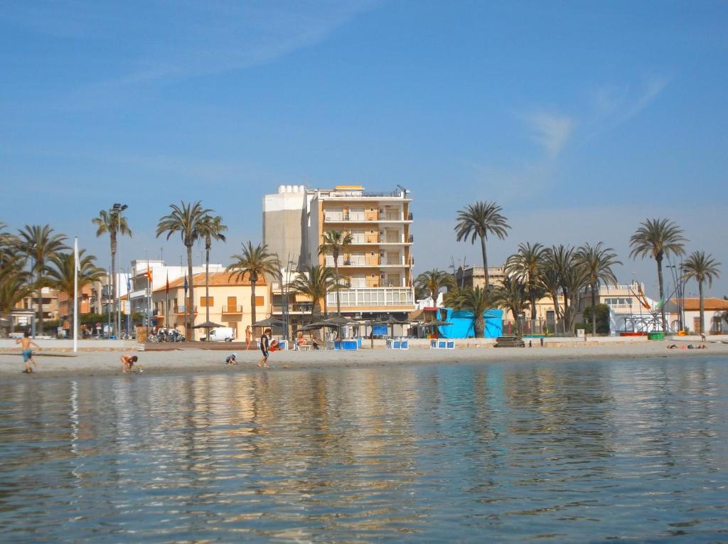 een uitzicht op een strand met palmbomen en een gebouw bij Hotel Lido in Santiago de la Ribera