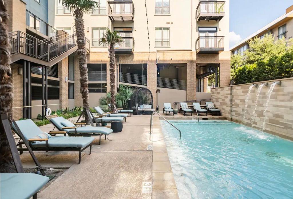 a swimming pool with lounge chairs next to a building at Charming 1,100 sq ft apartment near to The Shops at Legacy in Plano
