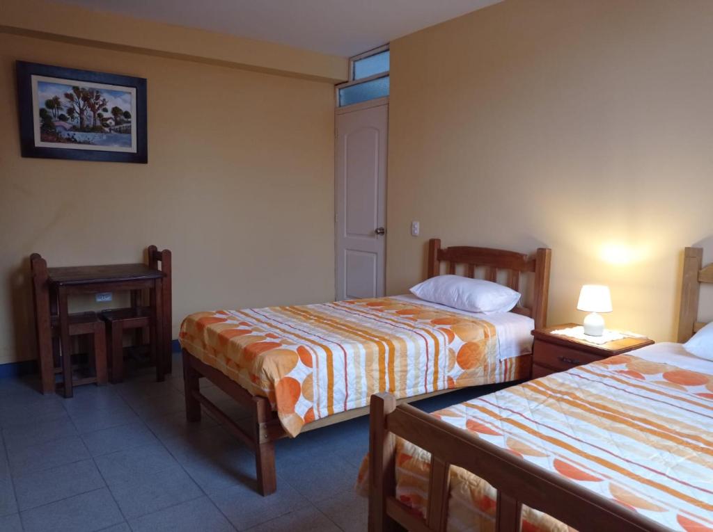 Habitación de hotel con 2 camas y mesa en Hostal Madrid, en Pisco