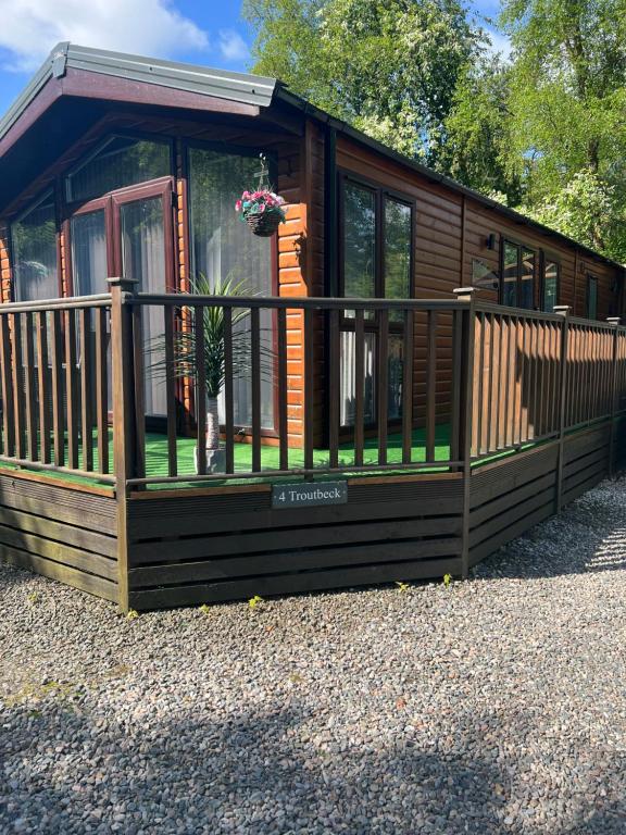 Cabaña de madera con porche y valla en Troutbeck Hot Tub Lodge 4, en Windermere