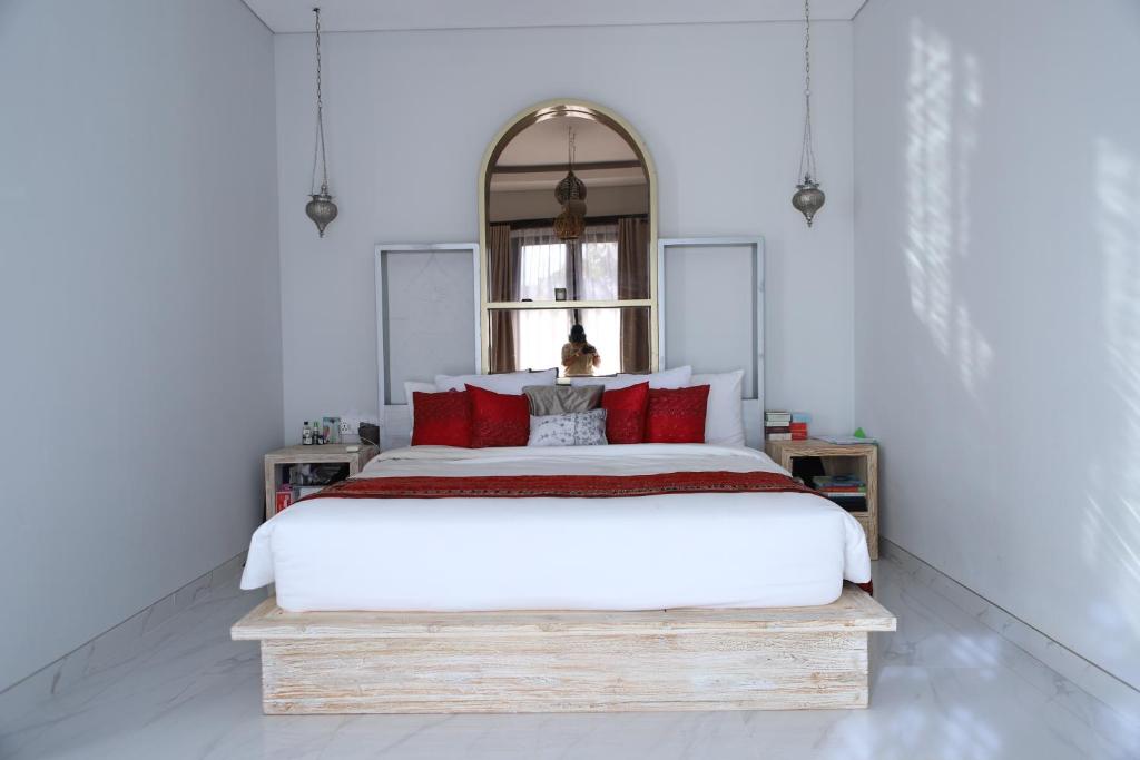 - une chambre avec un grand lit blanc et des oreillers rouges dans l'établissement Amour Eternel Villa, à Nusa Penida