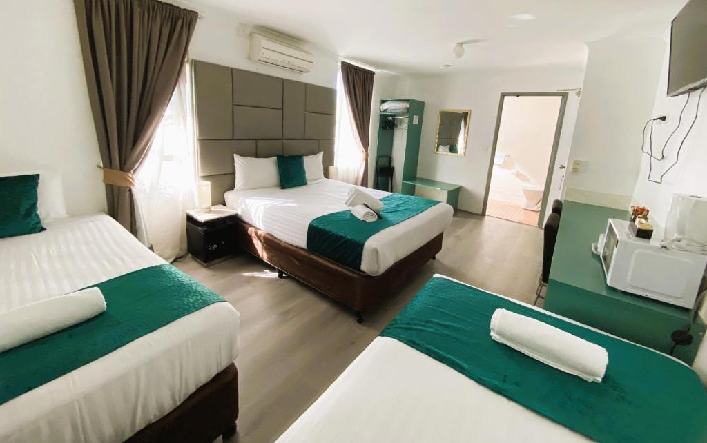 ein Hotelzimmer mit 2 Betten und einem Spiegel in der Unterkunft Hunter Valley Travellers Rest Motel in Cessnock